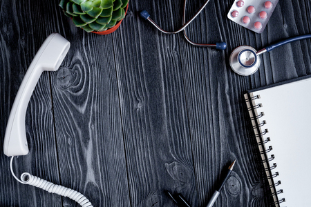 Entry to the doctor blank open notebook with stethoscope top view on dark wooden backgroundの写真素材