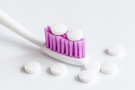 concept toothache with toothbrush and pills at white background close up