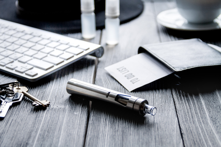 electronic cigarettes and mens dark wooden desktop close upの写真素材