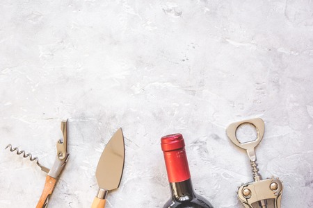 glass wine bottle and corkscrew on concrete background top view.