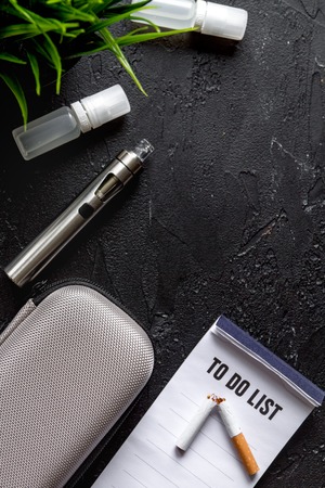concept of electronic cigarette on dark background top view.