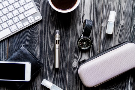 cup coffee, the electronic cigarette, men's accessories on dark wooden background top viewの写真素材