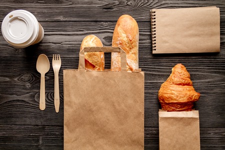 cup of coffee and bread in paper bag on wooden background top viewの写真素材