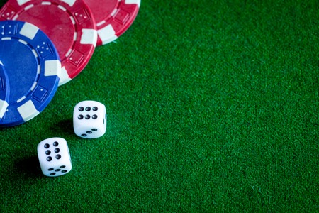 poker chips and dice on green background top view.