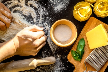 chef cooking pasta top view on dark background with hands
