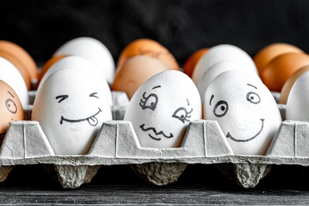 concept social networks communication and emotions - eggs smile on dark wooden backgroundの写真素材