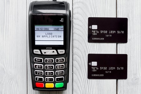 payment card through terminal in store top view on wooden background
