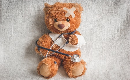 concept teddy bear childhood diseases at textile background close upの写真素材