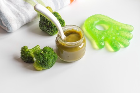 baby mashed with spoon in glass jar on white backgroundの写真素材