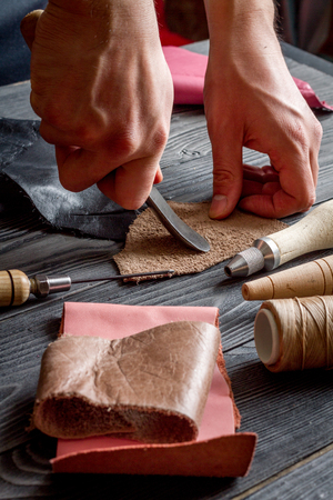 work in leather shop on dark wooden background close upの写真素材
