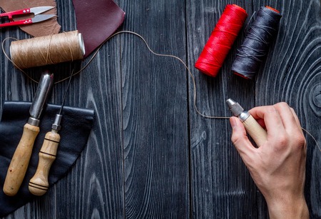 work in leather shop on dark wooden background top view