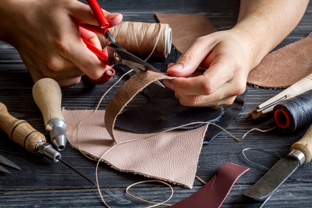work in leather shop on dark wooden background close upの写真素材