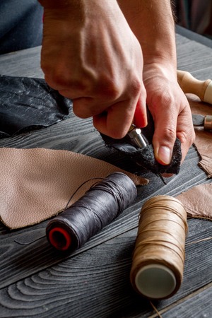 work in leather shop on dark wooden background close upの写真素材
