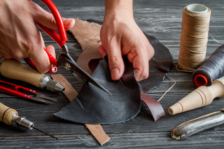 work in leather shop on dark wooden background close up