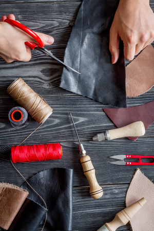 work in leather shop on dark wooden background top view