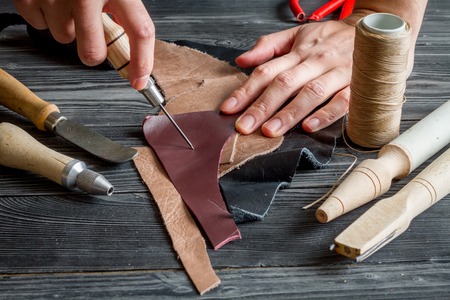 work in leather shop on dark wooden background close upの写真素材