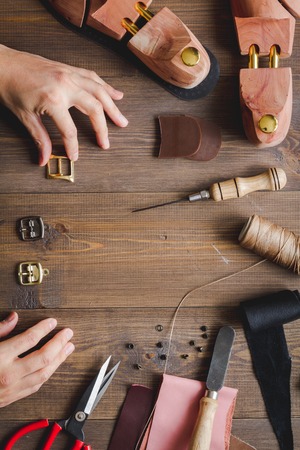cobbler tools in workshop on dark background close up with handsの写真素材