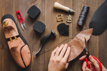 cobbler tools in workshop on dark background close up with hands