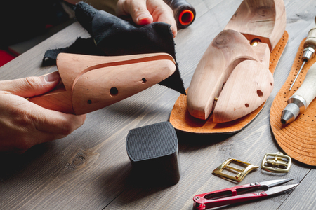 cobbler tools in workshop on dark background close up with handsの写真素材