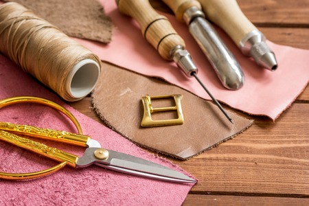 leather craft instruments on wooden background close up.