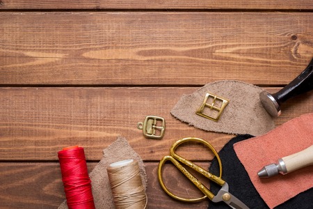 leather craft instruments on wooden background top view