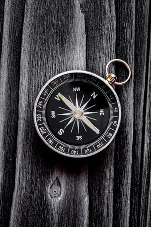 compass on dark wooden background concept direction of motion top view