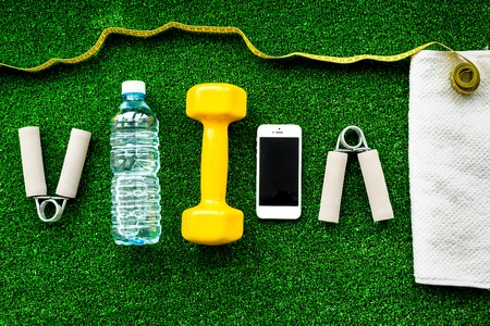 concept preparing to fitness sports equipment top view on green background.