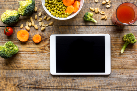 concept diet and tablet with vegetables mock up on wooden backgroundの写真素材