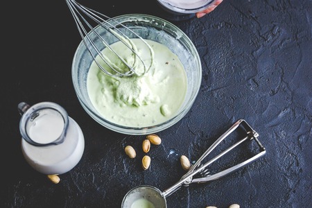 organic ice cream with pistachios homemade process on dark background with hands.
