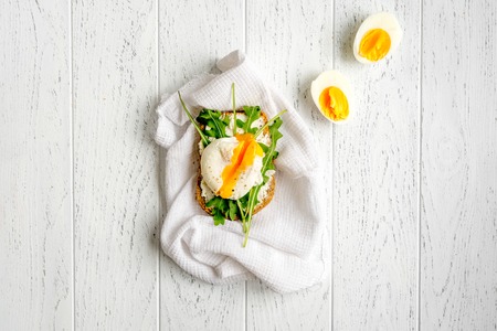 sandwich with poached eggs on wooden background top view mockup.の写真素材