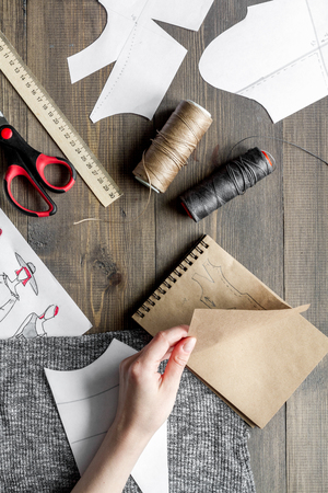 desktop designer clothes with tools top view at wooden table.の写真素材
