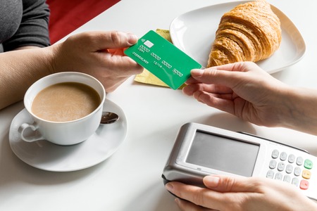 Credit card payment bill in cafe for croissant and coffee on white table backgroundの写真素材
