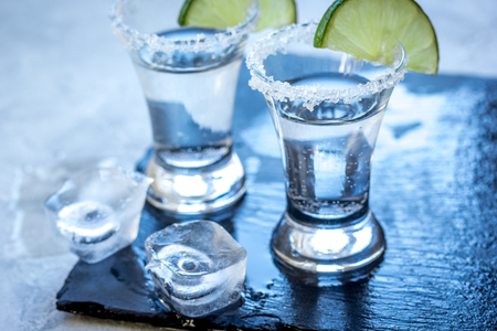 Silver tequila shots with lime and salt on gray stone backgroundの写真素材