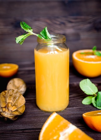 healthy orange cocktail with mint leaves in bottle on kitchen backgroundの写真素材
