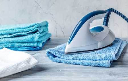 Towels pile with iron in housekeeping set on laudry backgroundの写真素材