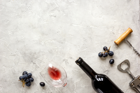 glass bottle of red wine with fresh grapes on stone texture background top view mock-upの写真素材