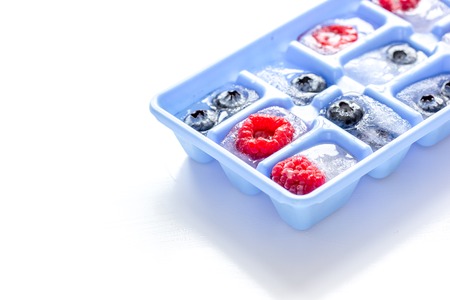 Ice tray with frozen berries on white background mockupの写真素材