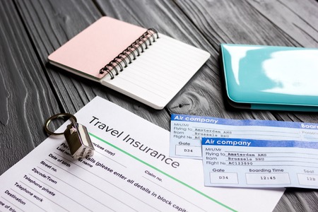 Traveling concept with insurance application and passport on wooden tableの写真素材