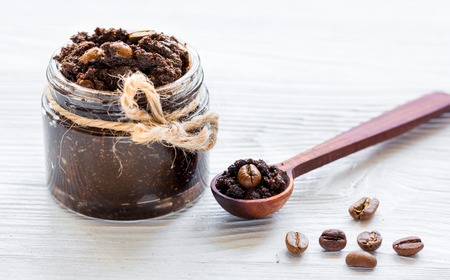 Homemade cosmetics with organic coffee scrub and beans on white desk backgroundの写真素材