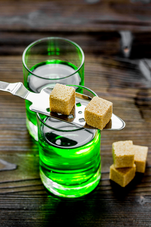 Absinthe shots with sugar cubes on wooden table background