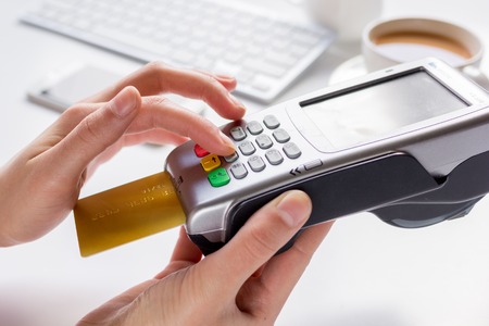Payment in cafe for business lunch concept with credit card and terminal on white desk background