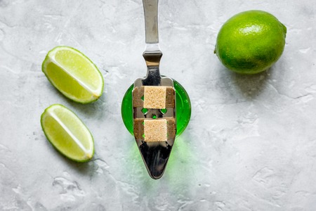 green absinthe in glass with fresh lime slices on stone table background top viewの写真素材