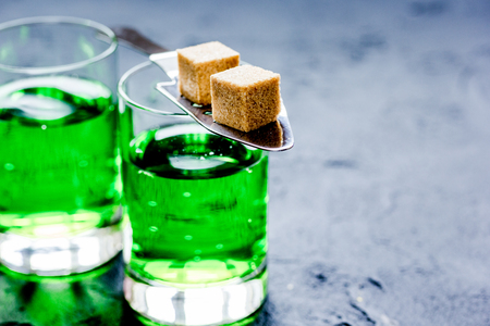 green absinthe with sugar cubes in spoon on dark table backgroundの写真素材