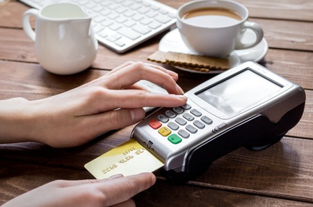 Payment for breakfast with card and terminal on wooden table backgroundの写真素材