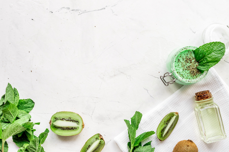 Organic body scrub and oil with fresh kiwi and mint in homemade cosmetics concept white table background top view mockupの写真素材