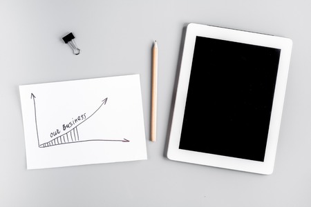 business plan development with tablet and graphic desk background top view mockupの写真素材