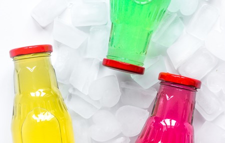 cold drinks in colorful plastic bottles with ice on white table background top view mock upの写真素材