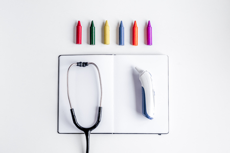 stethoscope, opened notebook on children's doctor office desk background top view mockupの写真素材