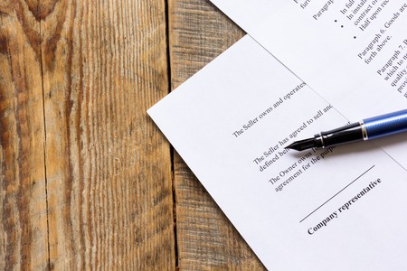 Wooden workspace with document and pen for sign for businessman day top viewの写真素材