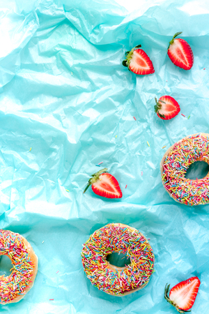 tasty lunch with colorful donuts and strawberry on blue table background top view mock upの写真素材